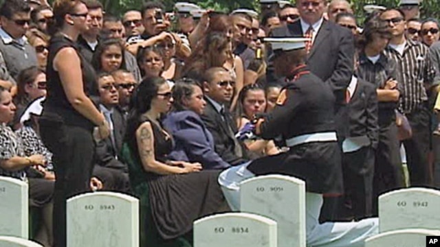 A marine presents the widow with a folded American flag.