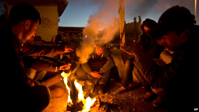 Afghan refugees gather around a fire to warm themselves in the early hours while waiting to get on board a ferry traveling to Athens, at the port of Mitylene on the northeast Greek island of Lesbos, Oct. 9, 2015.