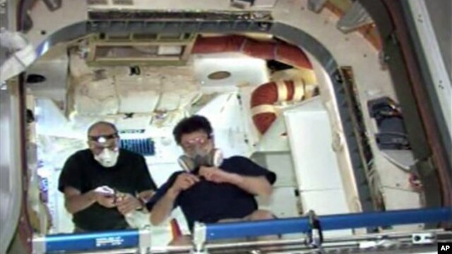 Space station astronaut Donald Pettit (L) and another astronaut work inside the Dragon spacecraft after entering for the first time, a day after Dragon's heralded arrival as the world's first commercial supply ship, May 26, 2012.