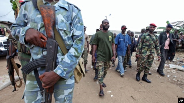 A man known as Commander Bauer, the chief of a group of pro-Ouattara fighters, walks with his men in northern Abidjan's Abobo district March 26, 2011