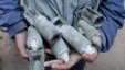 A boy holds unexploded cluster bombs after jet shelling by forces loyal to Syria's President Bashar al-Assad in the al-Meyasar district of Aleppo February 21, 2013.