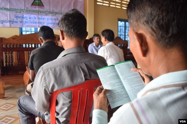 A member of the Grassroots Democratic Party (GDP) read the leaflet shared during the party meeting. The leaflet briefly describes the party policies, including a pathway for rural development, Takeo province, August 9, 2016. (S. Khan for VOA)