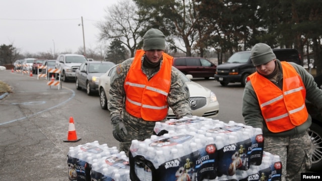 Michigan National Guard members distribute water to a line of residents in their cars in Flint, Michigan, Jan. 21, 2016.