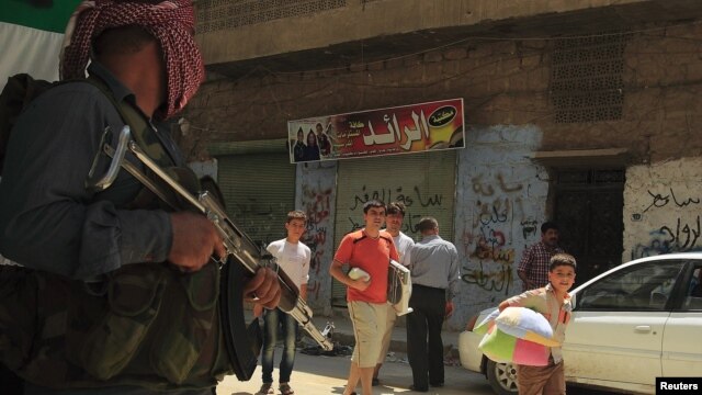 Fleeing civilians walk past a member of the Free Syrian Army in Aleppo's district of Salah Edinne July 31, 2012.