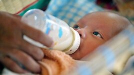 Cambodian orphan is fed formula milk by a nanny at Chrey Chao commune orphanage on the outskirts of Phnom Penh, May 12, 2004.