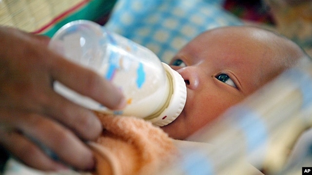 Cambodian orphan is fed formula milk by a nanny at Chrey Chao commune orphanage on the outskirts of Phnom Penh, May 12, 2004.