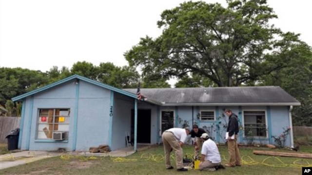 Engineers work in front of a home where sinkhole opened up underneath a bedroom and swallowed a man, in Seffner, Florida, March 1, 2013.