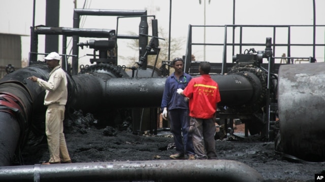 Sudanese workers inspect burnt out oil pipes at the oil-rich border town of Heglig, Sudan, April 24, 2012 (file photo).  