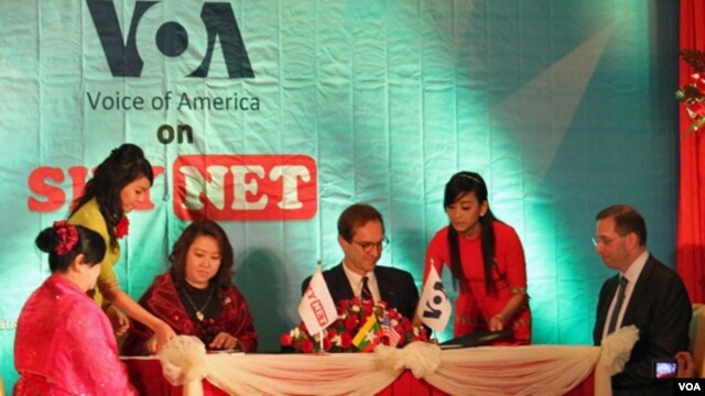VOA Director David Ensor (center right) along with Myint Myint Win (center left), Managing Director of Sky Net, sign the agreement to broadcast VOA content to Burma. US Ambassador Derek Mitchell (right) looks on.