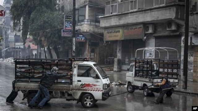 Syrian residents pull a truck that has run out of gas in Aleppo’s Sukari district, Dec. 7, 2012.