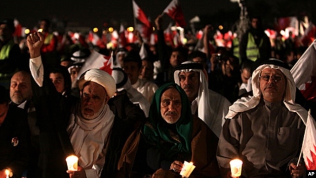 Bahraini  opposition leaders Hamza al-Dairi, second left raising his fist, and Jalal Fairooz, right, holding a candle and Bahraini flag, both former opposition lawmakers from al-Wefaq society, participate in a rally in the eastern village of Sitra, Januar
