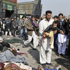 A man carries a wounded boy after a suicide blast targeting a Shi'ite Muslim gathering in Kabul, December 6, 2011