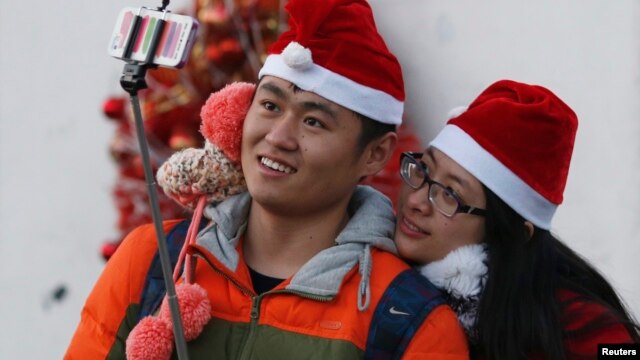 2014年12月24日，一对情侣带着圣诞帽在北京一所教堂里自拍。