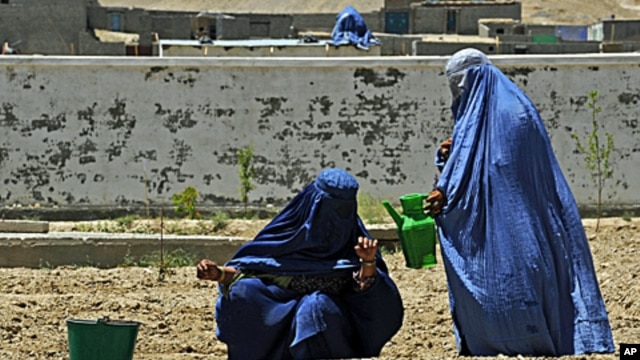 Two Afghan women water the soil at the Qalat Department of Women's Affairs, in the Zabul Province of Afghanistan, May 8, 2011