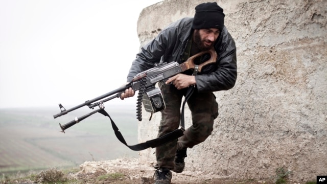 FILE - In this December 17, 2012 file photo, a Free Syrian Army fighter takes cover during fighting with the Syrian Army in Azaz, Syria.