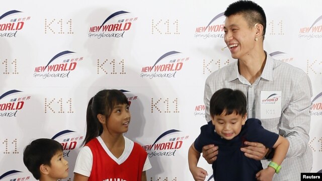 NBA basketball player Jeremy Lin (R) of the Houston Rockets holds up a child during a promotional event in Hong Kong August 24, 2012. Lin arrived in Hong Kong on Wednesday for his five-day Hong Kong tour. 