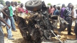 People gather around a car used by a suicide bomber following an explosion in church compound in Bauchi, Nigeria,  June 3, 2012.