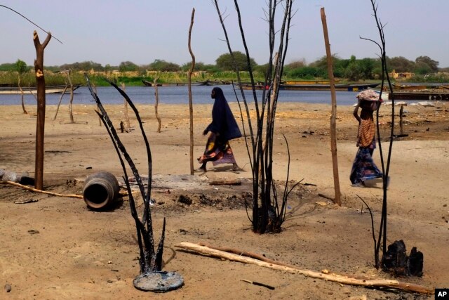 FILE - Chadian women walk past destroyed homes, in the Lake Chad shore village of N'Gouboua, March 5, 2015.