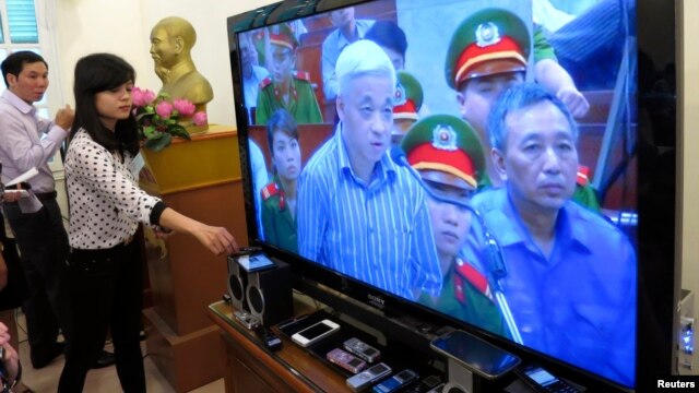 Phóng viên đặt thiết bị ghi âm cạnh màn hình TV trực tiếp từ phòng xử án tại Hà Nội, nơi ông Nguyễn Ðức Kiên bị xét xử, ngày 16/4/2014.