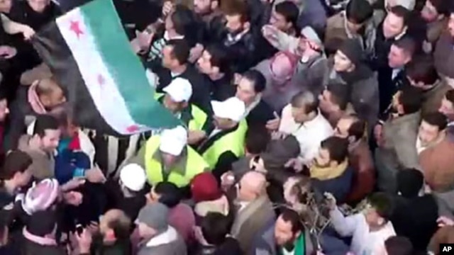 In this image from amateur video made available by the Shaam News Network and shot on Friday, Dec. 30, 2011, Arab League observers are seen at a protest in Idlib, Syria.