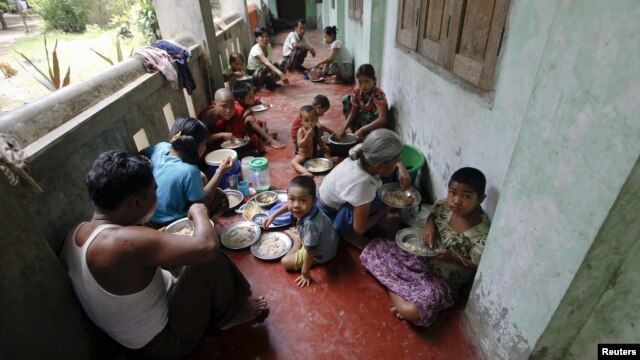 People eat food distributed at a Buddhist monastery used as a collective shelter for those displaced by recent violence in Sittwe, June 17, 2012.