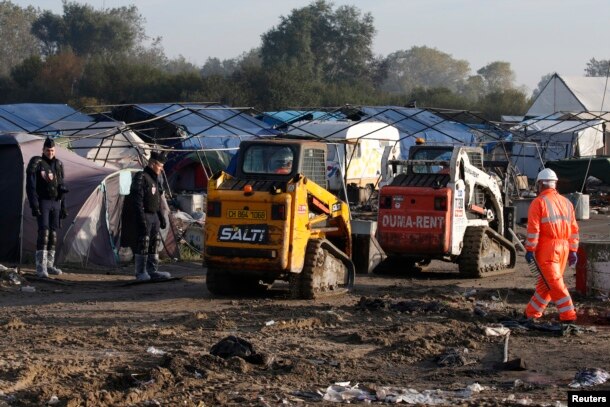 French CRS riot police secure the are as workmen and heavy machinery continue to tear down makeshift shelters and tents in the "Jungle" during the dismantlement of the camp in Calais, France, Oct. 27, 2016.