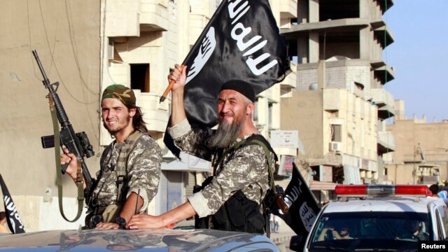 Fighters with the militant group Islamic State in Iraq and the Levant (ISIL, also called ISIS by some) wave flags as they take part in a military parade along the streets of Raqqa province, northern Syria, June 30, 2014. 