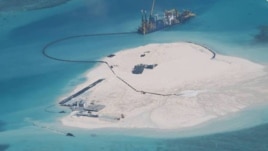 FILE - In this photo taken by surveillance planes and released May 15, 2014 by the Philippine Department of Foreign Affairs, a Chinese vessel, top center, is used to expand structures and land on the Johnson Reef at the Spratly Islands in the South China Sea, Philippines. 