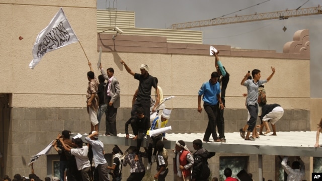 Một người biểu tình Yemen phất cờ trắng với hàng chữ "Không có Thiên Chúa, nhưng có Allah, và Mohammed là vị Tiên tri" phía trước Đại sứ quán Hoa Kỳ tại Sanaa, ngày 13/9/2012