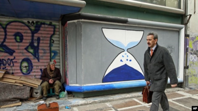 A shoeshine man sits in front of a closed shop with graffiti sprayed on its shutters in central Athens, Greece, March 12, 2012.