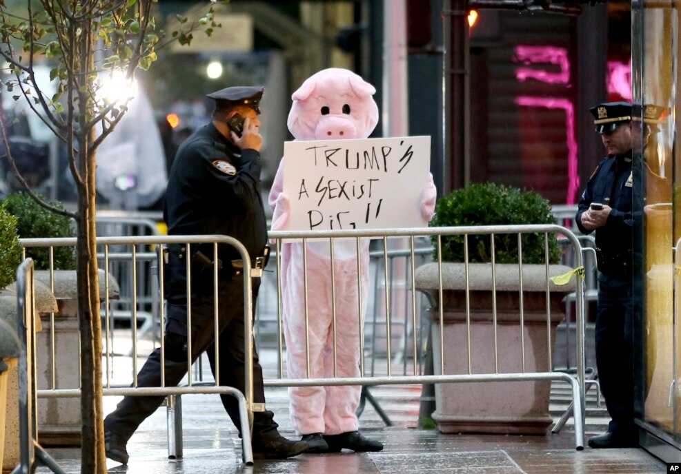 有抗议者装扮成一头猪，在川普大楼外面展示标语&ldquo;川普是搞性别歧视的猪&rdquo;
