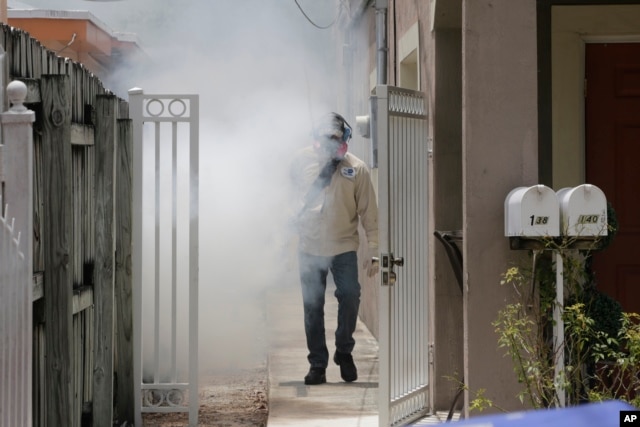 A Miami-Dade County mosquito control worker sprays around a home in the Wynwood area of Miami, Aug. 1, 2016.