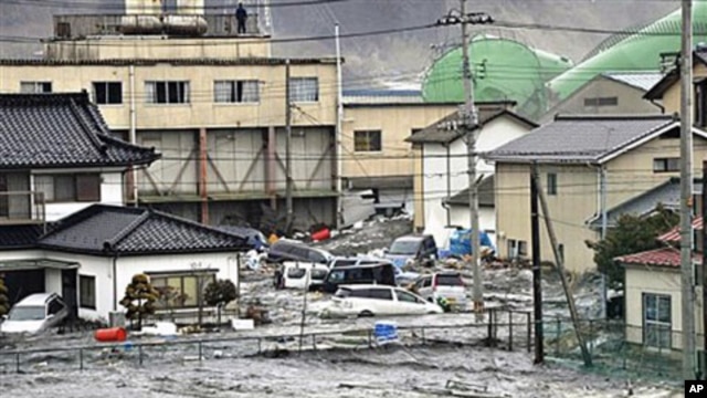 An earthquake-triggered tsunami washes away a warehouse and vehicles in Kesennuma, Miyagi prefecture (state), Mar 11 2011