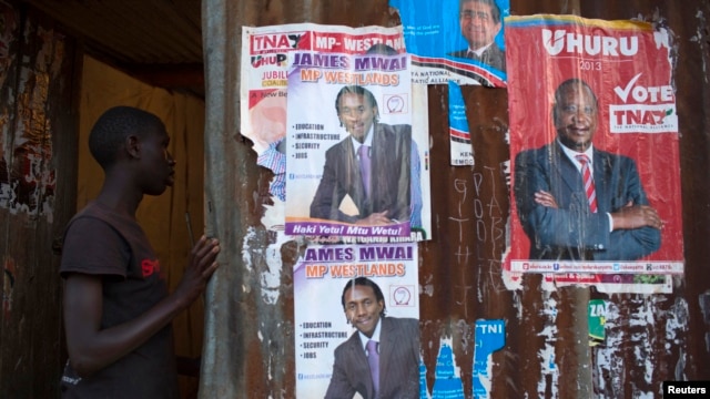 A boy enters an house with various campaign posters at the Kangemi slum in Kenya's capital Nairobi, February 28, 2013. 