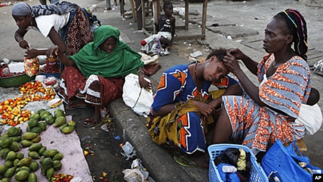 A woman braids her friend's hair at a market in the Abobo neighborhood of Ivory Coast's main city Abidjan, April 17, 2011.
