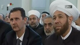 An image grab taken from the state-run Syrian TV shows Syria's embattled President Bashar al-Assad (L) siting next to Grand Mufti Ahmed Hassun during a prayer to mark the birth of  Islam's Prophet Mohammed in Damascus, January 24, 2013. 