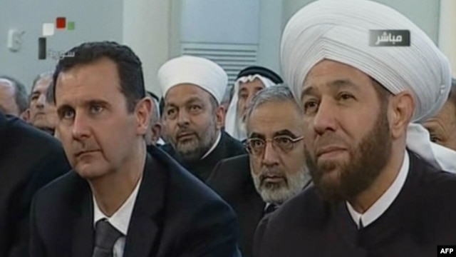 An image grab taken from the state-run Syrian TV shows Syria's embattled President Bashar al-Assad (L) siting next to Grand Mufti Ahmed Hassun during a prayer to mark the birth of  Islam's Prophet Mohammed in Damascus, January 24, 2013. 