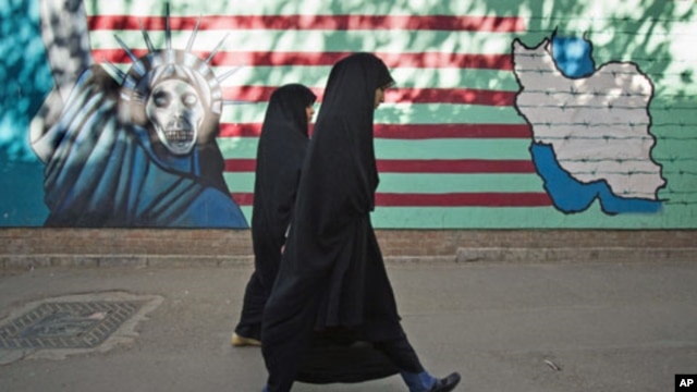 Iranian women walk past an anti-U.S. mural on the wall of the former U.S. embassy in Tehran, Iran, October 12, 2011.