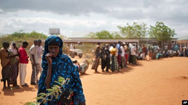 A Somali woman stands in front of Somalis queuing outside the reception center in Ifo refugee camp, one of three camps in Kenya's Dadaab refugee complex on July 25, 2011