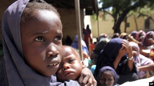 An internally displaced Somali girl carries her sibling as they wait to collect food relief from the World Food Program (WFP) at a settlement in Mogadishu August 7, 2011.