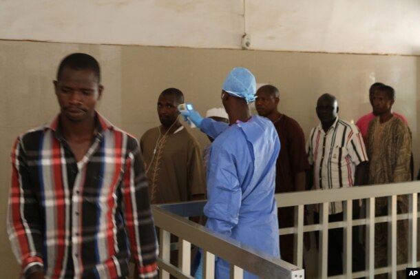 A health worker takes the temperature of people to see if they might be infected by the Ebola virus inside the Ignace Deen government hospital in Conakry, Guinea, March 18, 2016.