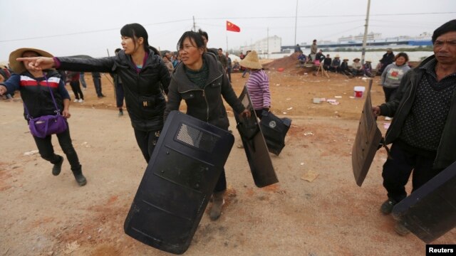Dân làng mang khiên lấy được của cảnh sát trong cuộc đụng độ ở Côn Minh, tỉnh Vân Nam, ngày 15/10/2014.