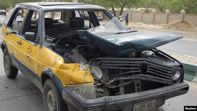 A car damaged by a bomb blast is seen in front of police headquarters in Nigeria's northeastern city of Maiduguri June 8, 2012.