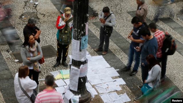 Người dân đứng xem danh sách việc làm tuyển dụng trên 1 1 đường chính ở trung tâm thành phố Sao Paulo, 13/8/2014.