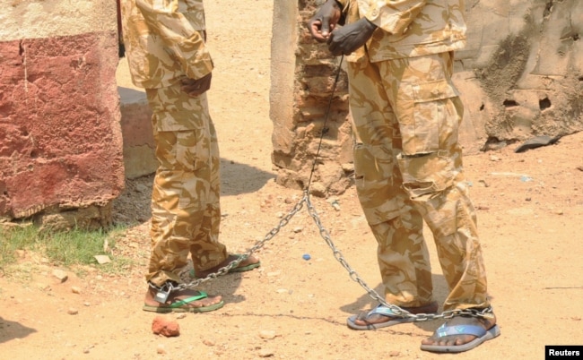 FILE - South Sudanese soldiers suspected of beating and raping civilians are chained together at the presidential guard unit, within the Sudan People's Liberation Army headquarters, after their arrest in Juba, March 3, 2017.