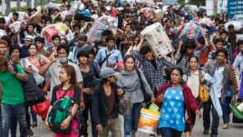 Cambodian migrant workers carry their belongings as they walk to cross the border at Aranyaprathet in Sa Kaew, June 15, 2014.