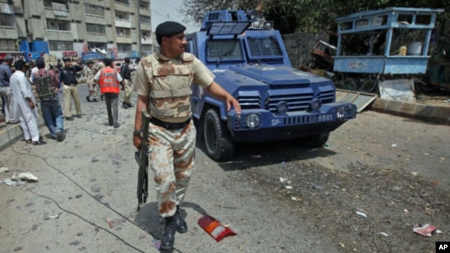 A paramilitary soldier walks past a police armored personnel carrier, which was hit by a bomb attack in Karachi, Pakistan, April 5, 2012.