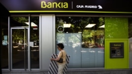 woman walks by an ATM cash machine at a branch of the Bankia bank in Madrid, June 6, 2012.