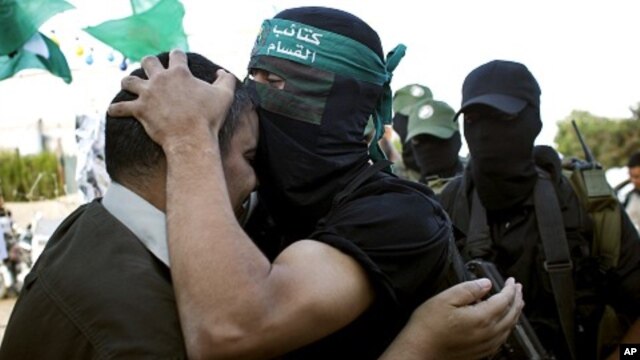 A masked Hamas militant kisses freed Palestinian prisoner Mahawish al Qadi, left, who was involved in organizing the abduction of Israeli soldier Gilad Schalit, in Rafah, southern Gaza Strip, Oct. 19, 2011.