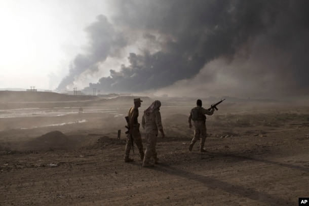Iraqi army soldiers man a checkpoint as oil wells burn on the outskirts of Qayyarah, Iraq, Oct. 19, 2016.